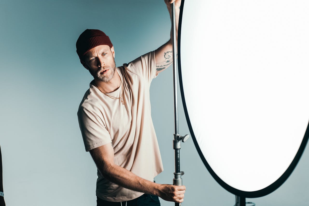 A professional photographer adjusting studio lighting while posing indoors.